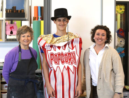 Kathy Schultz (left) and Brittany Culjan (right) pictured with their student, Killian (middle), dressed as Professor Popcorn, the mascot for the student-led popcorn business.
